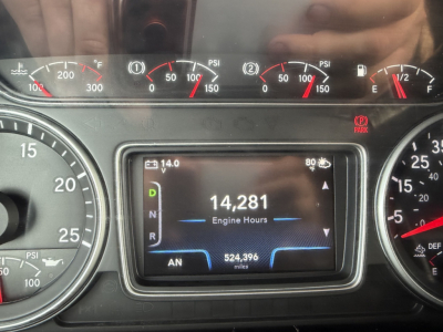 Instrument cluster and digital display in a truck cab showing engine hours 14,281 and 524,396 miles. Various gauges with PSI and temperature indicators visible around the display.