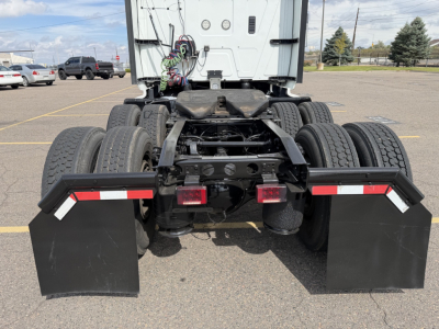 Rear view of a 2019 International LT625 truck tractor chassis with dual rear axles, dual tire sets, black mudflaps, and red/white reflective tape on the side guards.
