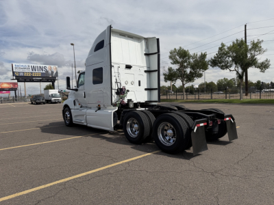 Truck tractor in a parking lot showing International LT rear chassis and dual rear axles with fifth wheel, cab doors, and white paint.