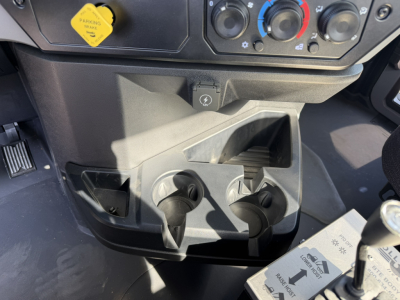 Dashboard area of a 2026 Mack GR64F roll-off truck showing controls and two cup holders in the center console with climate knobs above.