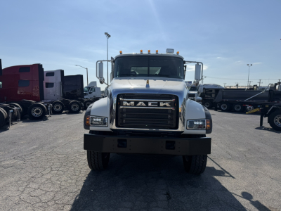 Front view of a white 2026 Mack GR64F roll-off truck showing grille with MACK badge and large bumper, in a dealership lot.