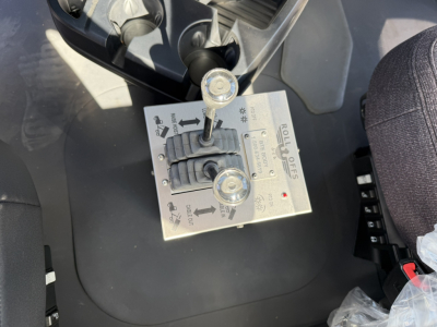 Rolloff control panel with levers and knobs mounted on a Mack GR64F cab interior showing arrows, labels, and screw terminals.
