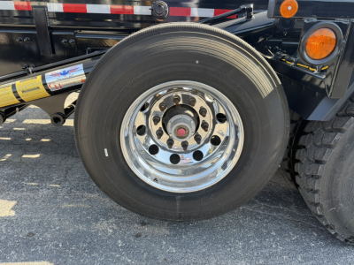 Mack GR64F wheel and tire close-up showing polished chrome rim and hub, part of front axle assembly.