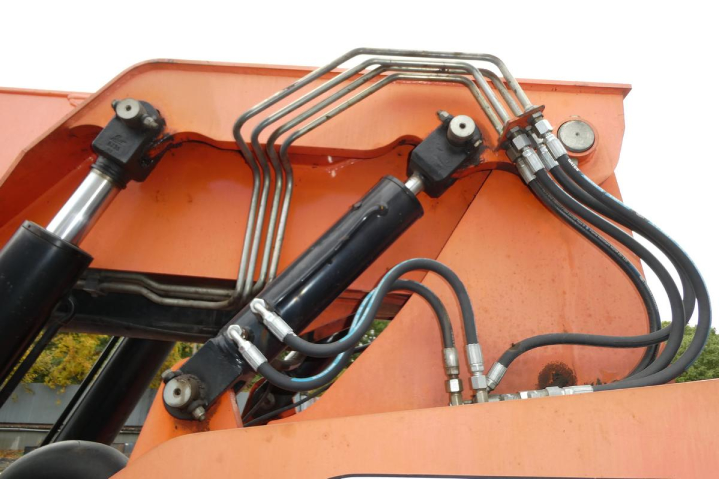 JLG 6042 boom lift hydraulic cylinders and hoses with metal lines and orange body.
