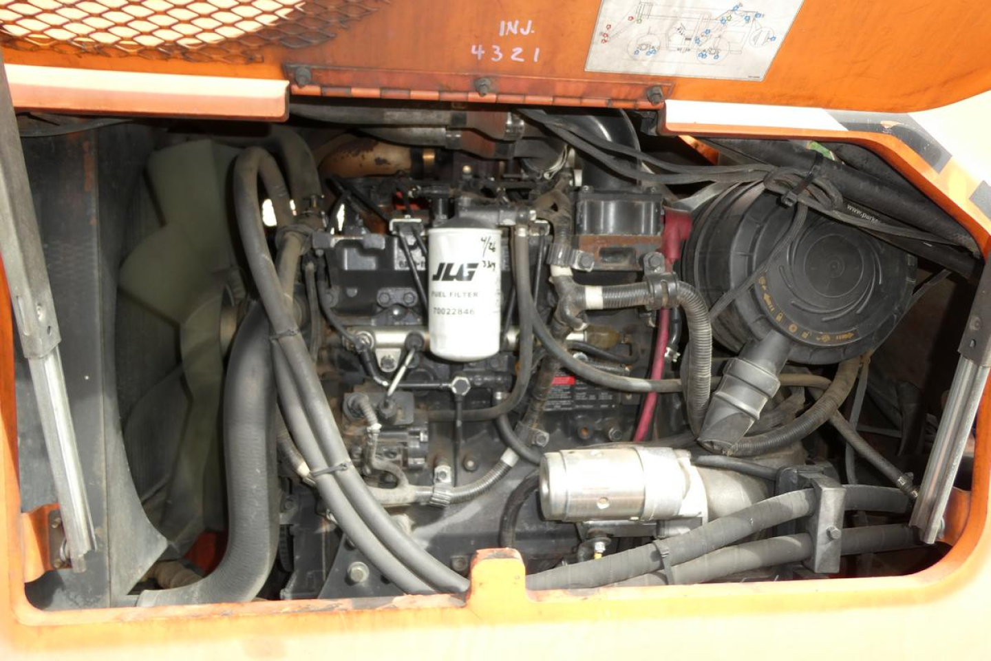 JLG 6042 telescopic lift engine bay showing engine with filter, hoses, and hydraulic components.