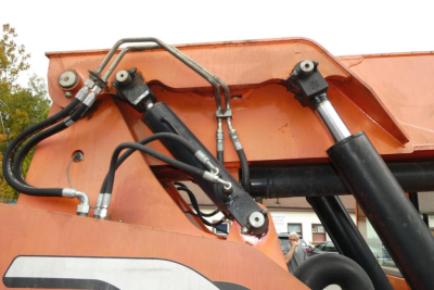 Telescopic boom lift hydraulic hoses and cylinders on orange JLG 6042 aerial lift showing hydraulic lines and control linkage.