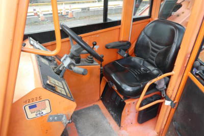 Cab interior of a JLG telescopic lift showing 6042 model control station with steering wheel and black seat.
