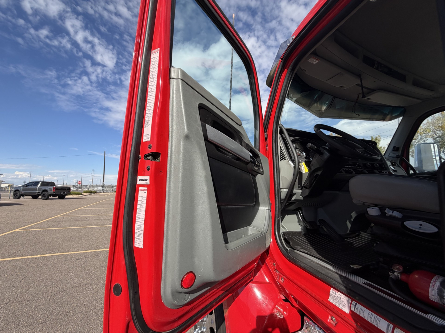 Kenworth T880 cab interior and door area with red exterior, driver door open showing dashboard and steering wheel.