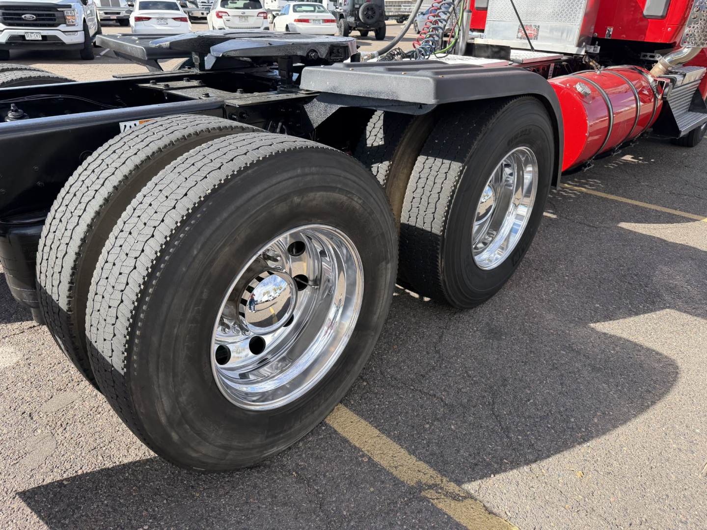 Kenworth T880 wheel area showing dual rear axles with polished chrome rims and heavy tires.