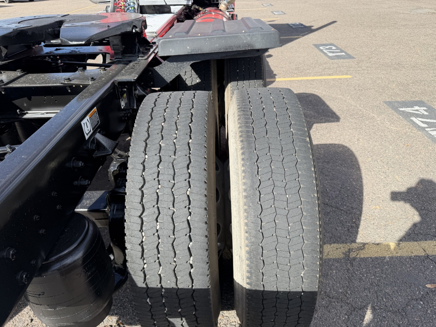 Twin rear truck tires on a 2020 Kenworth T880 conventional daycab tractor chassis showing dual rear wheels and part of the frame.