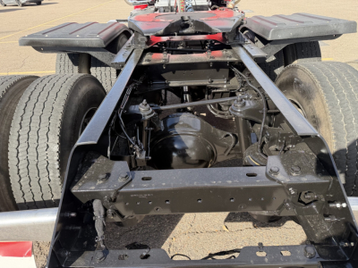 Kenworth T880 chassis cab rear view showing frame rails, dual rear axles, and drivetrain components with suspension and U-bolts visible.