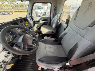 Kenworth T880 cab interior showing steering wheel, dashboard, two front seats with seat belts, and center console.