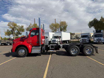 Kenworth T880 side view chassis with red cab and empty flatbed area, showing front and rear wheels and a white box behind cab.