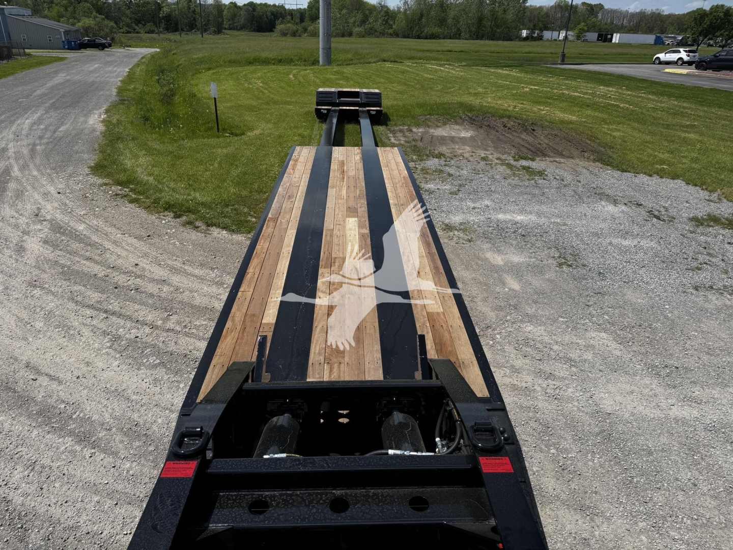 Flatbed trailer deck with wooden planks and black channel frame showing on a new Fontaine XN20 lowboy trailer.