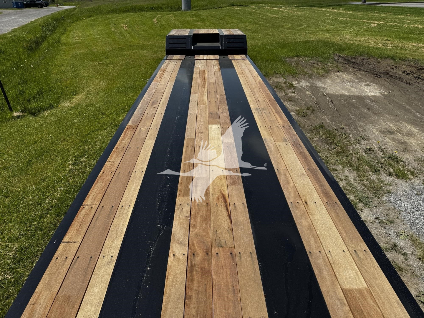 Lowboy trailer bed with wooden planks and black accents, Fontaine logo watermark across center, viewed from front toward hitch area.