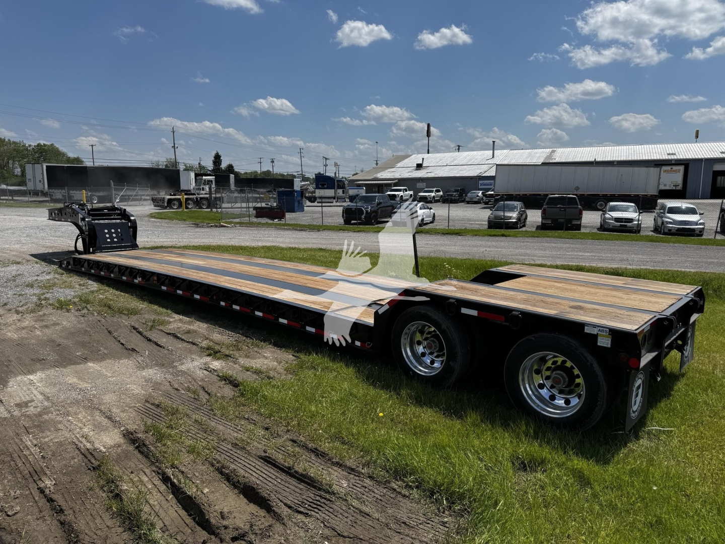 Tow trailer on a grassy lot showing a lowboy trailer with wood deck and dual-axle configuration.