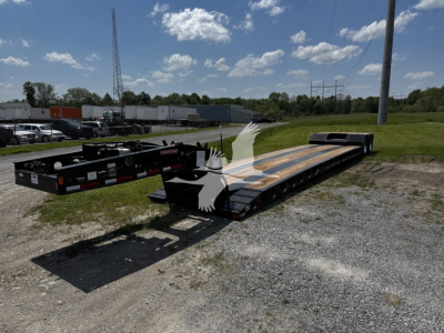 Fontaine Xn20 lowboy trailer showing long flatbed with wooden deck sections and a gooseneck hitch area in a gravel lot.