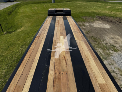 Lowboy trailer bed with wooden planks and black accents, Fontaine logo watermark across center, viewed from front toward hitch area.