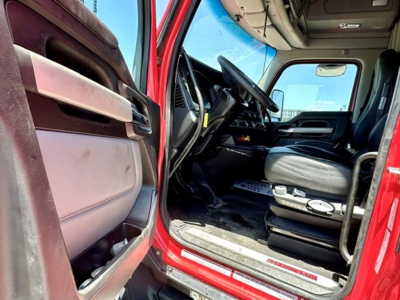 Kenworth T680 truck interior view from open driver door showing steering wheel, dashboard, and driver's seat.