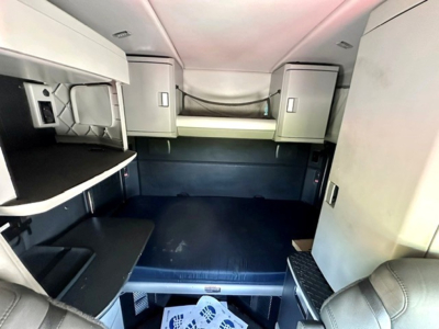 Kenworth T680 sleeper cab interior showing bunk bed, storage cabinets, and seating area.