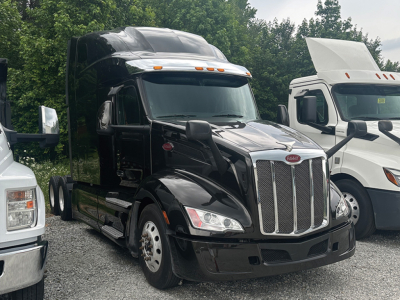 Peterbilt 579 tractor-trailer in black view from front-left angle with chrome grille and sleeper cab.