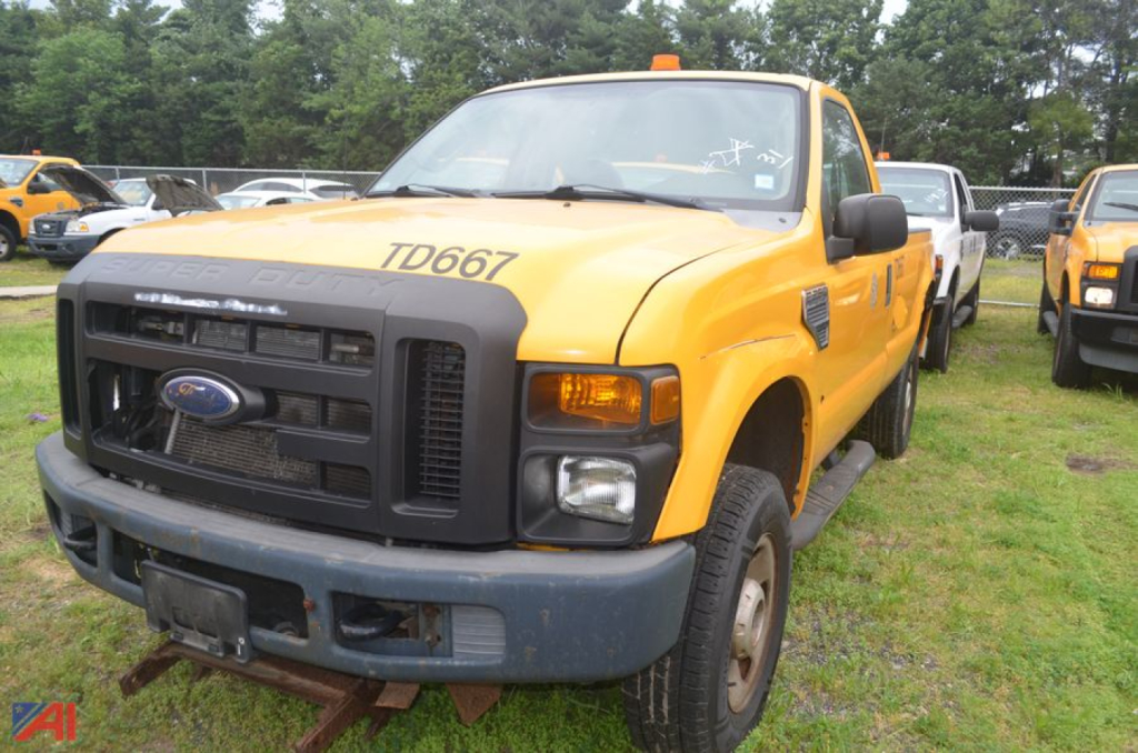Ford F-250 Super Duty dump truck front-left view showing yellow cab, black grille, TD6671 markings, amber clearance light on roof, and front bumper.