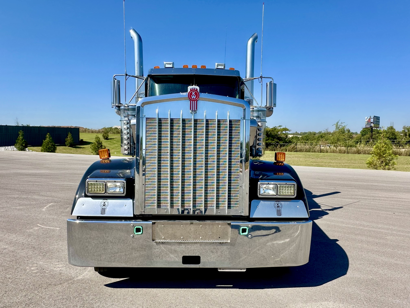 Kenworth W900L front view showing chrome grille, bumper, and dual stacked exhaust stacks.