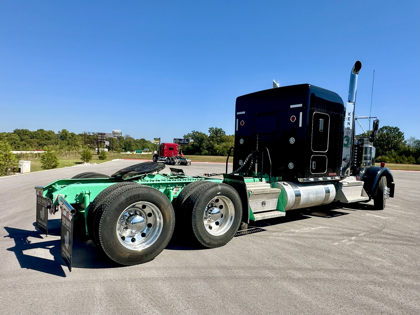 Kenworth W900L tractor chassis rear view showing dual rear axles and green frame with black sleeper cab.