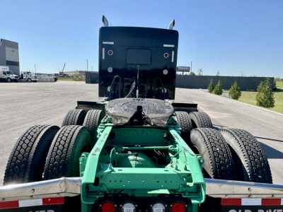 Kenworth W900L chassis rear view showing green frame, dual drive axles, and fifth wheel mounting with back of cab.