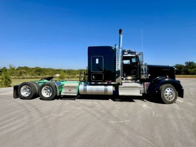 Kenworth W900L conventional sleeper truck side view showing tandem rear axles and exhaust stacks.
