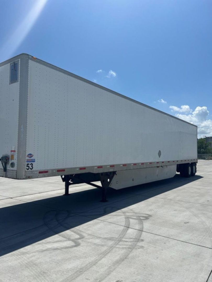 Utility van trailer showing long white enclosed box with side decals and dual rear axles.