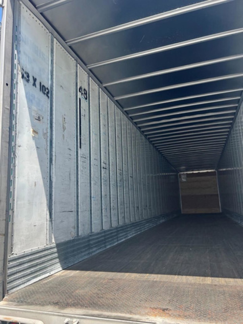 Trailer interior showing metal wall panels with numbered markings and a long rectangular cargo area.