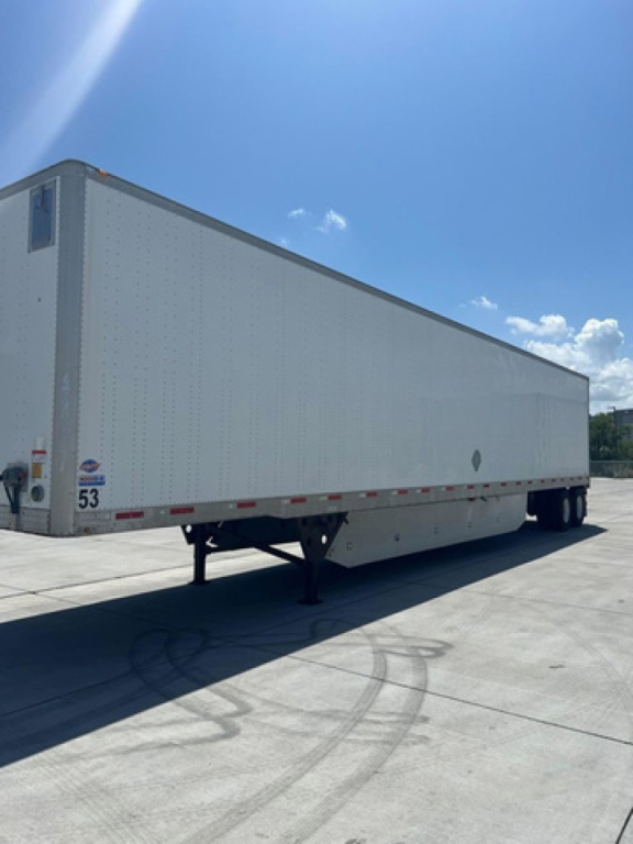 Utility van trailer showing long white enclosed box with side decals and dual rear axles.