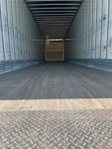 Trailer interior view showing empty cargo area with metal sidewalls and diamond plate floor, van trailer.