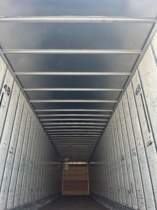  trailer interior showing metal box truck cargo area with ribbed walls and ceiling, long narrow perspective toward rear door, numbers 4B8 on side frames