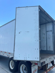 Trailer back and side view of a white utility van trailer with open rear doors, showing metal interior and dual rear wheels.