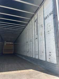 Trailer interior showing side walls with vertical metal ribs and numbered markings, open cargo area.