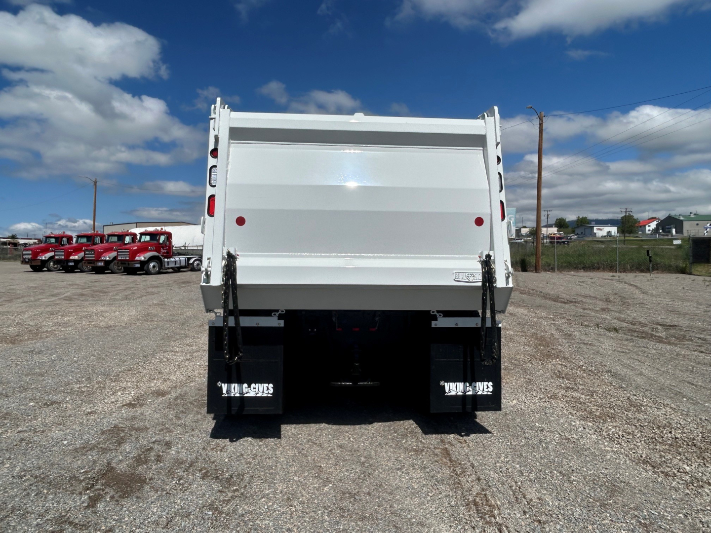 Rear view of a white 2025 Mack GR104B dump truck with a high-sided dump bed, tailgate, and black mud flaps.