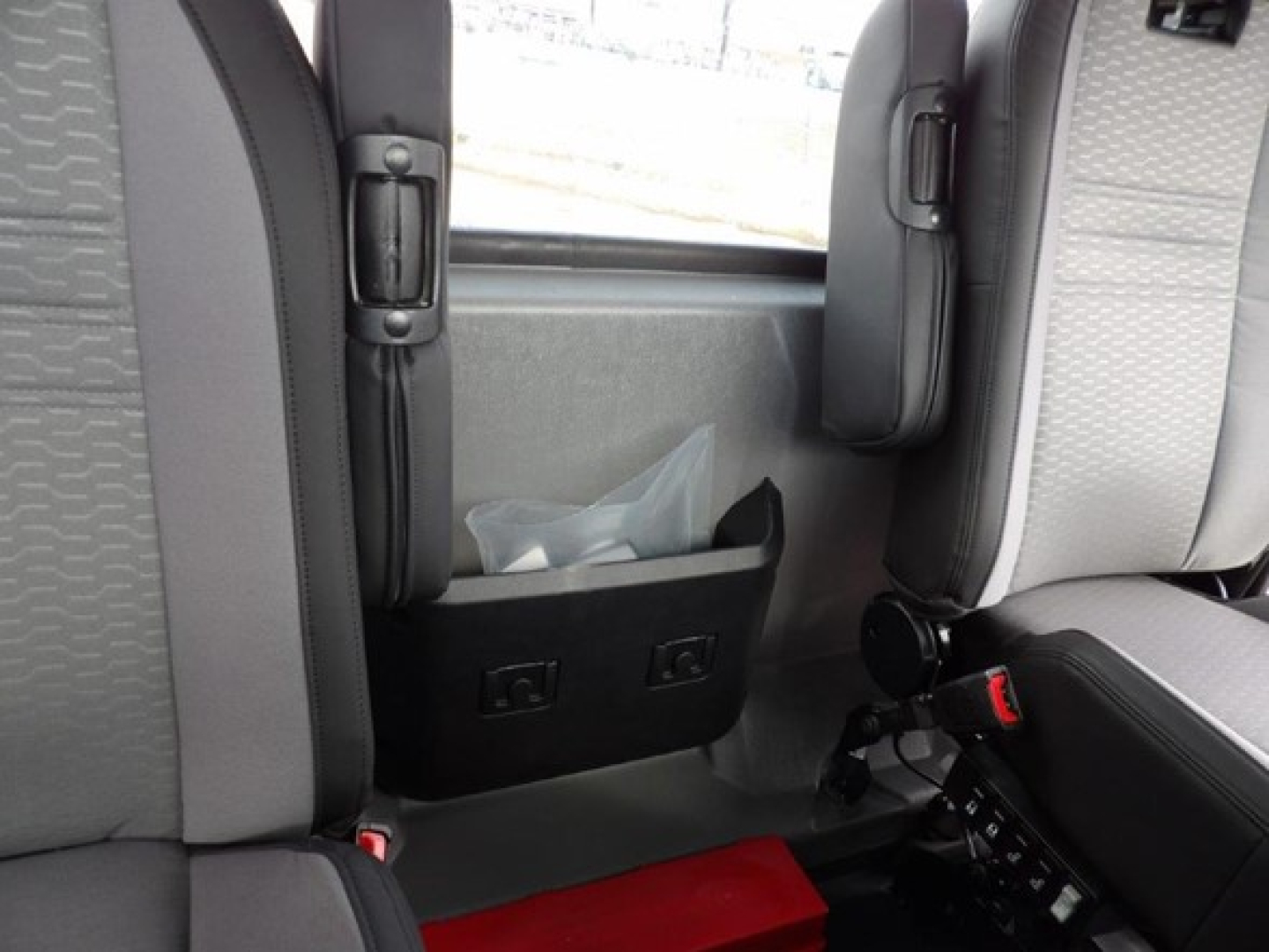 Cab and chassis interior seating area showing black storage pocket and seatbelt anchors.