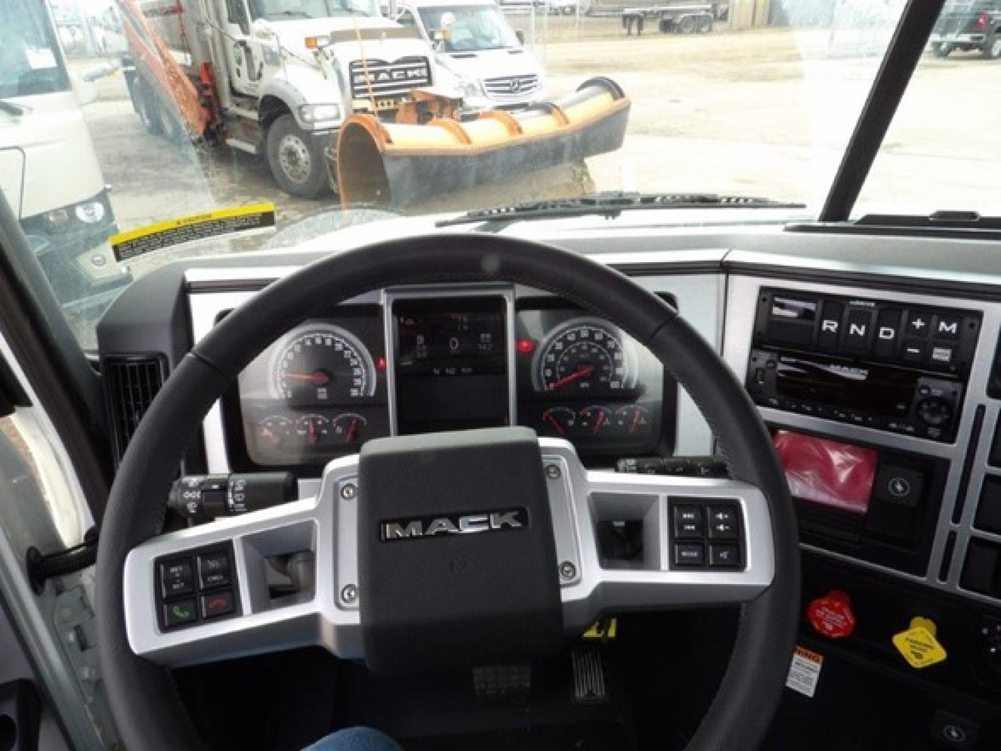Mack GR64B cab and chassis interior showing steering wheel, dashboard gauges, and gear selector with N R D M indicators.