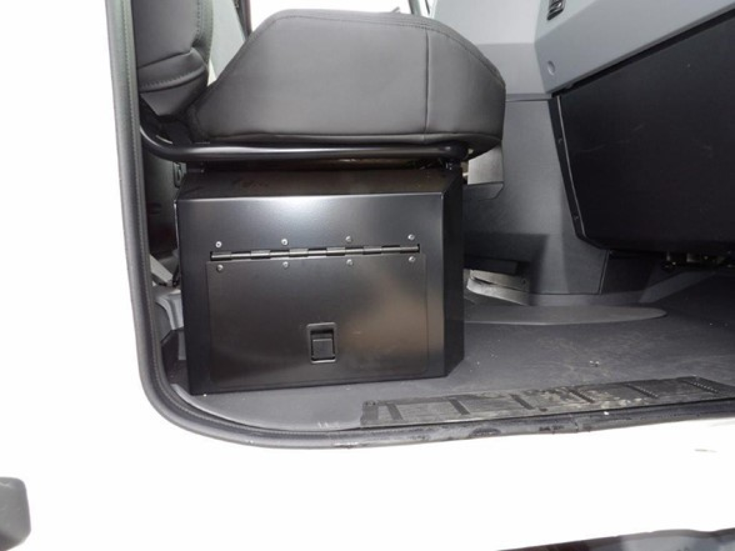 Cab and chassis interior showing under-seat storage toolbox with a hinged lid on the left side of the cabin floor.