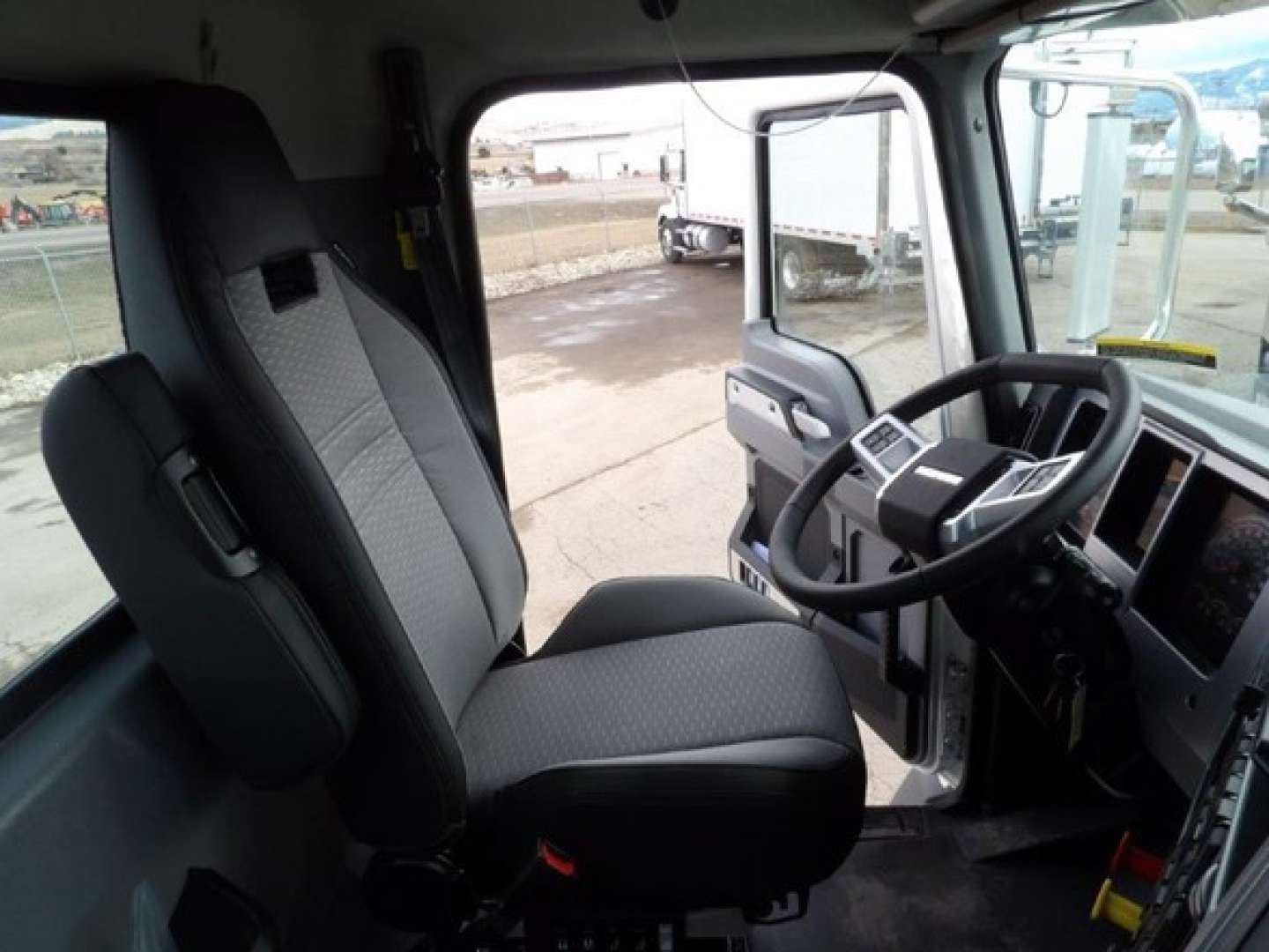 Cab interior of a 2025 Mack GR64B showing front seats and steering wheel view from driver side door