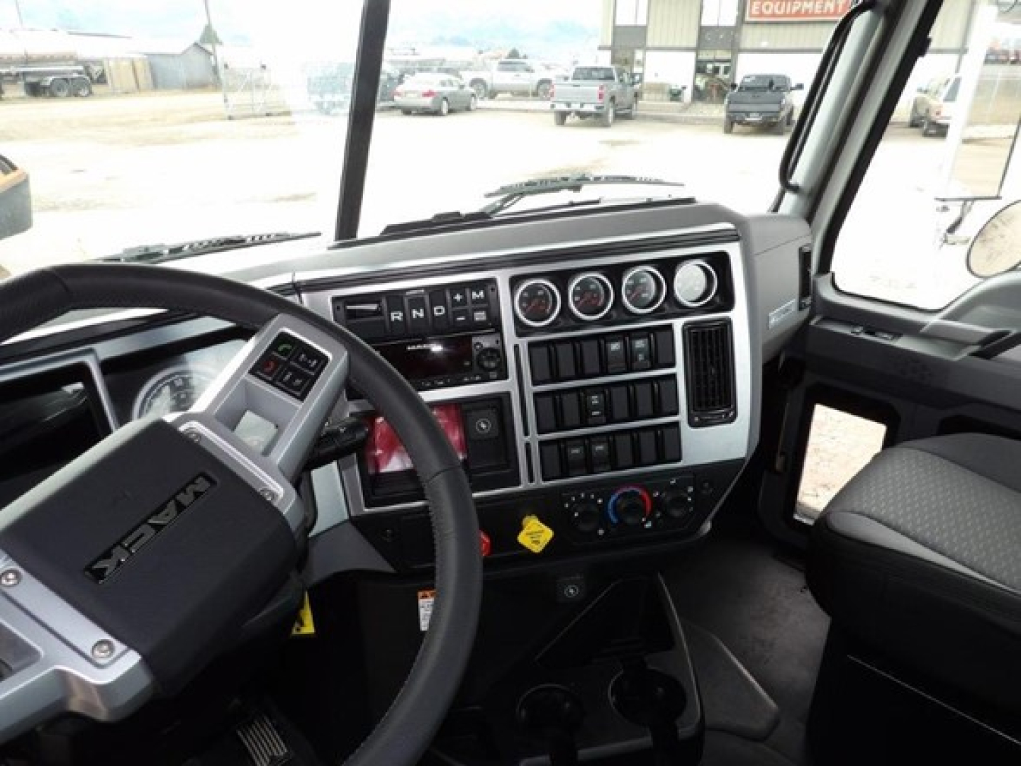 Front cab interior of a 2025 Mack GR64B showing steering wheel, dashboard gauges, and control panel.