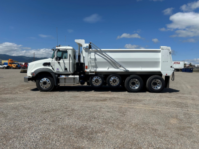 Dump truck side view showing 2025 Mack GR104B with white cab and large dump body, multiple axles, chrome exhaust stack, and fuel tanks.