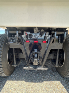 Rear underside of a Mack GR104B dump truck showing hitch, dual rear wheels, and suspension components.