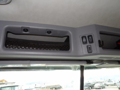 Mack GR64B cab interior overhead console area with switches and storage net, showing part of windshield and dashboard edge.