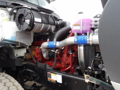 Mack GR64B engine bay showing red engine block, purple coolant reservoir, blue hose clamps, and black chassis.