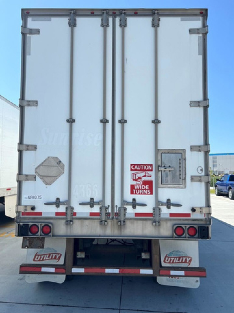 Rear view of a white utility van trailer with double doors, metal latches, warning stickers, and red/white reflective tape.