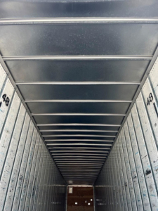 Trailer interior vertical walls with numbered markings and overhead ribs; long narrow cargo area seen from the back opening.