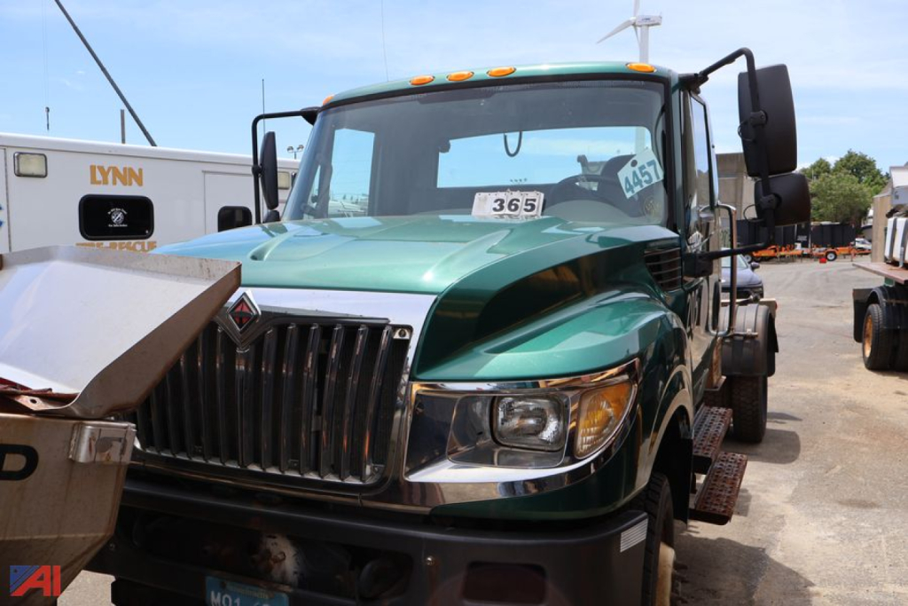 Truck cab front view of a green 2015 International TerraStar with a Swaploader hooklift in a yard.